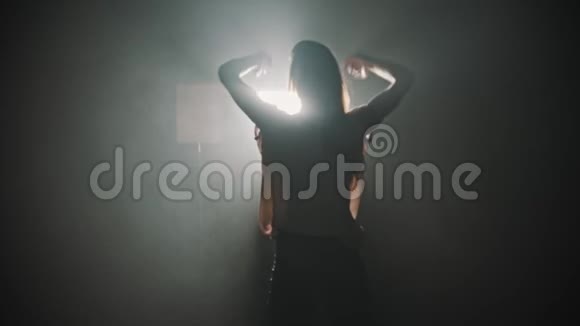 一个年轻女子的剪影双手放在明亮灯光的背景上跳舞视频的预览图