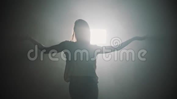 一个女人在明亮的灯光背景下双手舞动的剪影视频的预览图