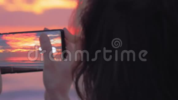 女人手中的智能手机拍摄日落视频的预览图