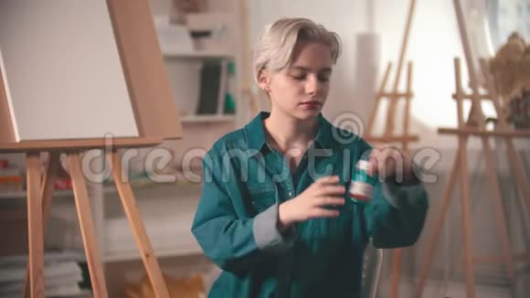 一位年轻的女艺术家打开了一个蓝色的颜料筒视频的预览图