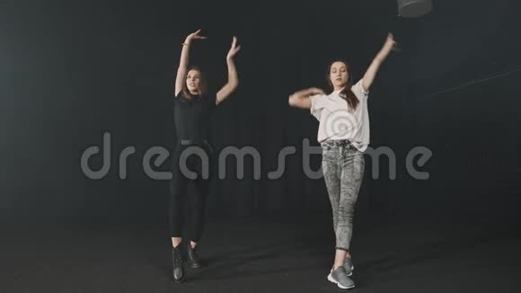 两个年轻女子在黑暗工作室训练舞蹈视频的预览图