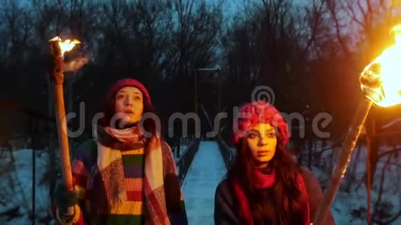 两个年轻的女性朋友晚上在桥上散步手里拿着燃烧的火把环顾四周视频的预览图