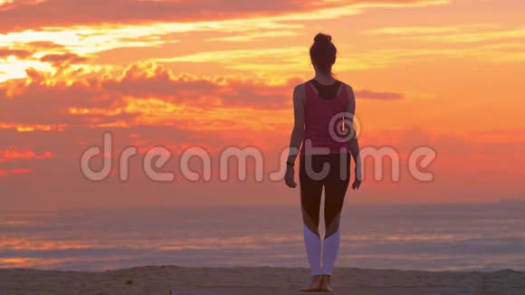 女人在沙滩上练习瑜伽夏日日落视频的预览图