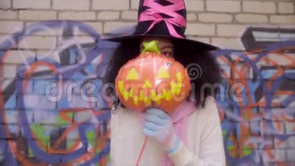 穿着女巫帽的可爱的黑人少女在万圣节扮脸视频的预览图