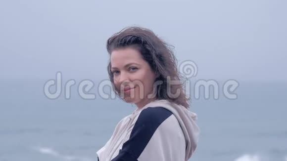 灰色雨天海滩上一个蓝眼睛女人的肖像视频的预览图