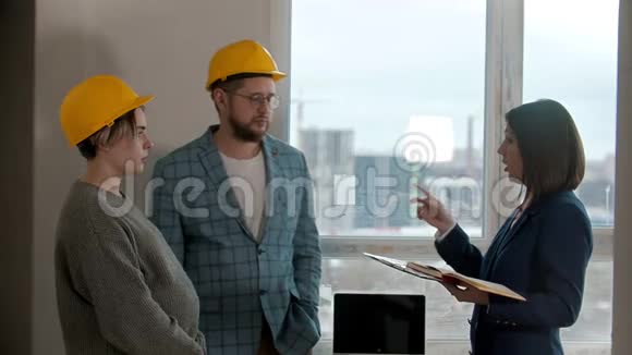 一个怀孕的女人和她的丈夫一起在新公寓里看着一个男人和房地产经纪人说话视频的预览图
