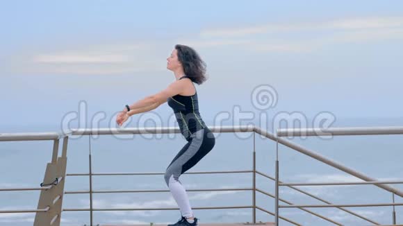 穿运动服的强壮女人在海滨做蹲式运动视频的预览图