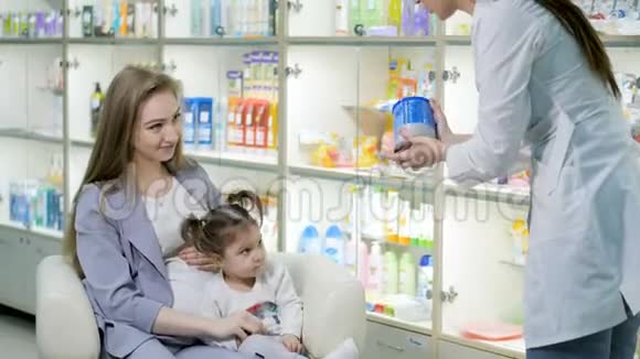 年轻的女药剂师给怀孕的顾客提供建议带着可爱的女婴医药商店概念视频的预览图