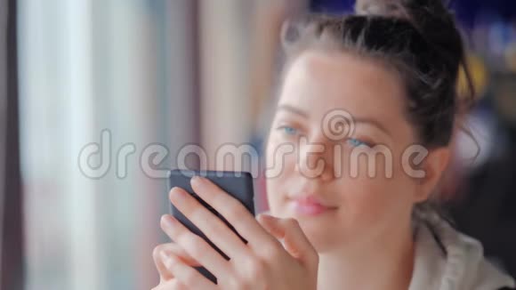 美丽的女人在咖啡馆里用她的手机读消息视频的预览图