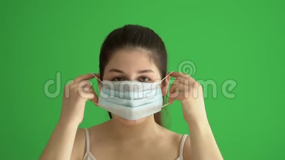 蒙面妇女保护自己免受流行病的侵袭年轻女性戴着绿色屏幕上的医疗面具特写照片视频的预览图