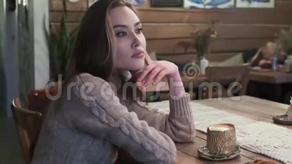 可爱的年轻亚洲美女坐在桌子上无聊地在舒适的咖啡馆喝咖啡视频的预览图