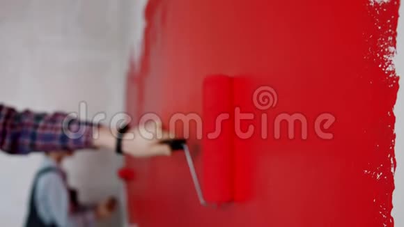 公寓装修父亲和儿子用红色油漆覆盖墙壁视频的预览图