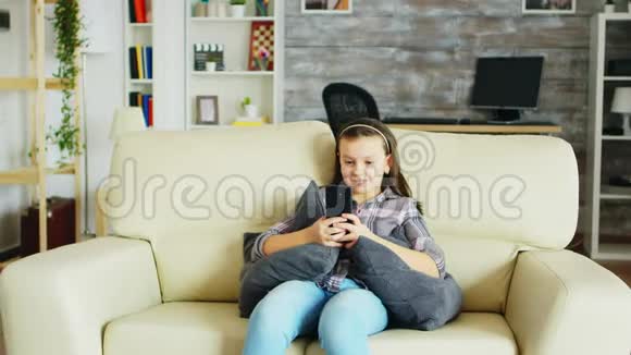 快乐的小女孩带着牙套坐在沙发上视频的预览图
