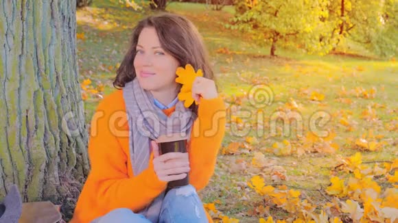 秋天花园里穿羊毛衫喝茶的美女视频的预览图