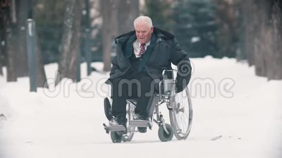 一位坐在轮椅上的老人试图在雪地上移动视频的预览图