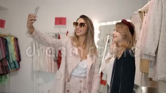 魅力女人用智能手机在时尚精品店录制视频视频的预览图