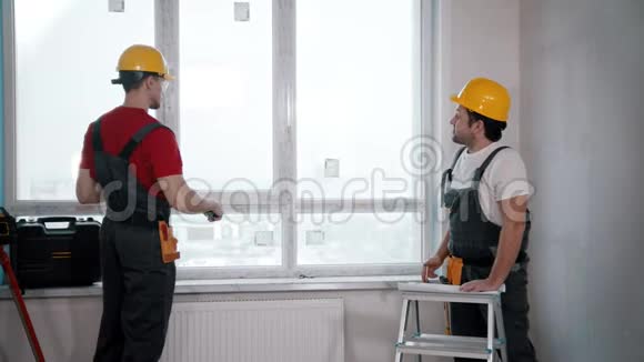 房间里的公寓维修两名工人测量一个有大窗户的区域视频的预览图