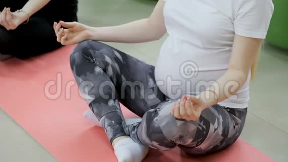 一群快乐的孕妇在健身房锻炼瑜伽和冥想莲花姿势视频的预览图
