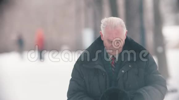 一位孤独的老人站在雪地公园里视频的预览图