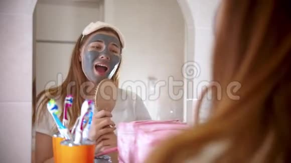 一个年轻漂亮的女人脸上戴着面具在浴室的镜子前跳舞唱歌玩得很开心视频的预览图
