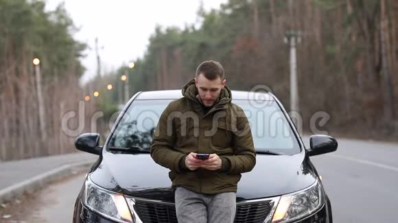 一个人靠在车盖上打着电话视频的预览图