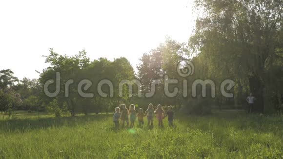 阳光明媚的夏日一大群孩子穿着便服微笑着在公园里奔跑视频的预览图