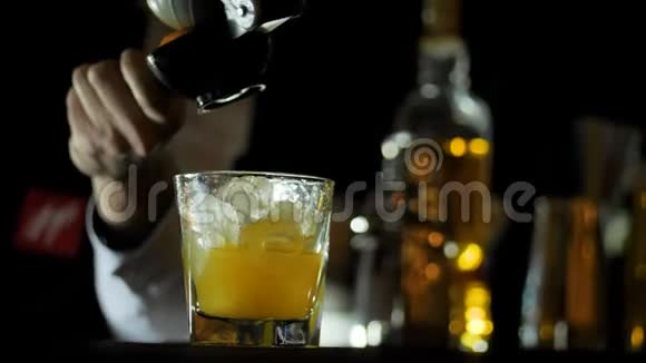 酒保在酒吧柜台为威士忌鸡尾酒制作新鲜橙汁视频的预览图