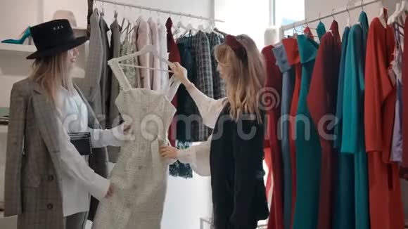 快乐的年轻女士在现代购物中心的陈列室讨论服装设计视频的预览图