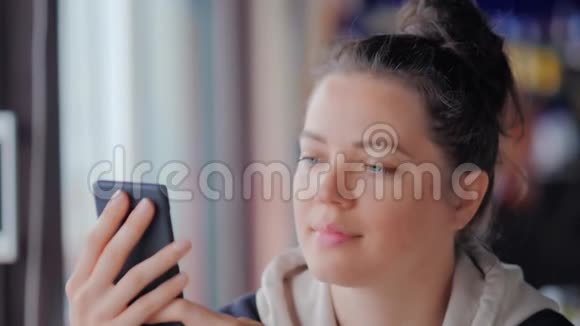 一位年轻女士在咖啡厅为自己的智能手机自拍视频的预览图