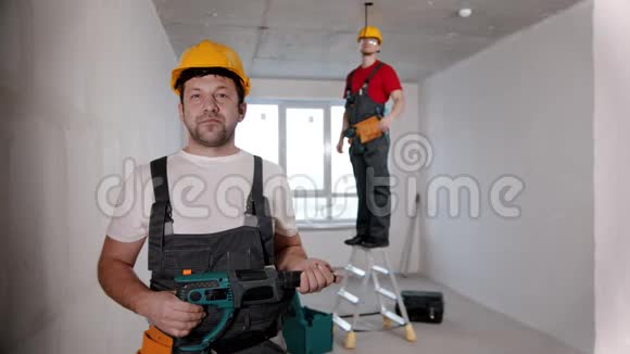 选秀室的公寓维修一名男子工人站在摄像机前把钻头递给另一个人视频的预览图