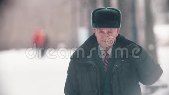 一位老人摘下帽子从雪地上把帽子清理干净视频的预览图