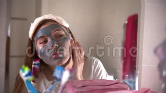 一位年轻女子在浴室里从脸上洗掉了面具视频的预览图