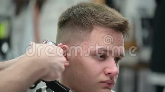 理发店那个年轻人的发型主裁剪头发的特写镜头头后有剪刀视频的预览图