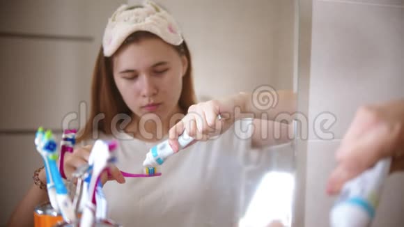一位年轻女子在刷子上涂牙膏视频的预览图