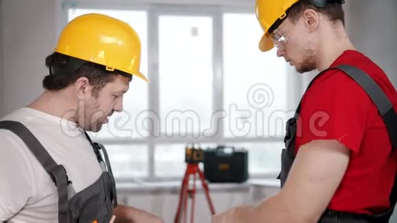 公寓维修两名工人在工作前在纸上讨论公寓计划视频的预览图