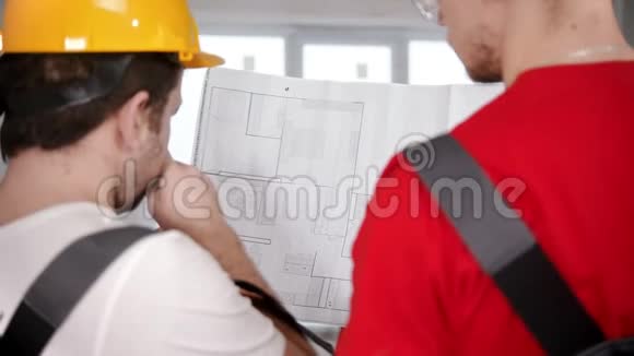 两名工人在工作前在报纸上讨论公寓计划视频的预览图