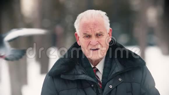 一位老人站在户外下雪的时候举起双手摸着他的头视频的预览图