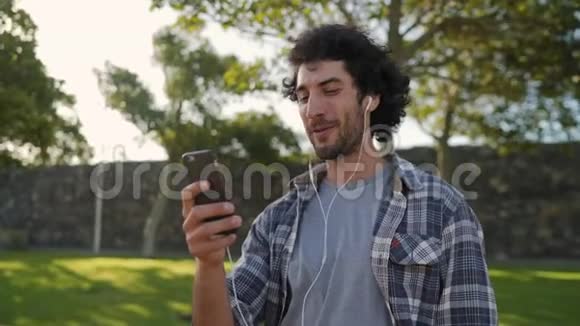 穿着格子衬衫的开朗的年轻人通过智能手机打视频电话挥手在手机屏幕上微笑视频的预览图