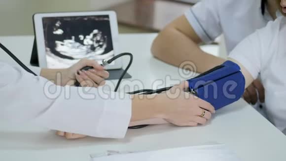怀孕医生用血压计测量血压并咨询年轻夫妇患者视频的预览图