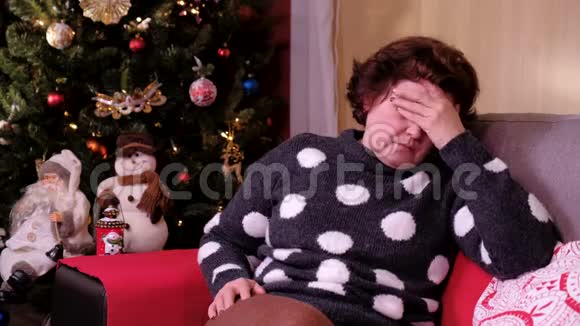 沮丧的女人躺在客厅的沙发上装饰着圣诞节假期和新年的概念视频的预览图