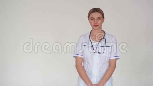 一位穿着白色制服的漂亮女医生脖子上戴着听诊器双臂交叉在胸前这就是视频的预览图