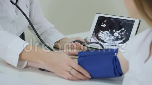 怀孕医生用血压计测量血压并咨询年轻夫妇患者视频的预览图
