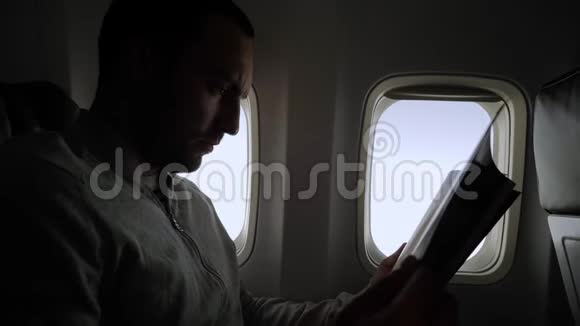 在飞机舱里读杂志的年轻人视频的预览图