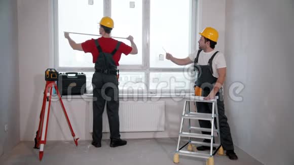 房间里的公寓维修两名工人测量从墙到窗户的距离视频的预览图