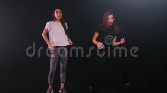 两个年轻女子在黑暗的工作室跳舞视频的预览图