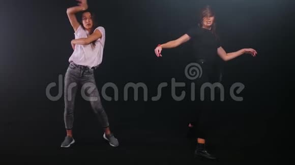 两个年轻女子自由式舞蹈在黑暗的工作室视频的预览图