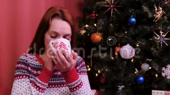 快乐的年轻女子在家喝着一杯热巧克力圣诞节假日和人的概念假期及假期概念视频的预览图