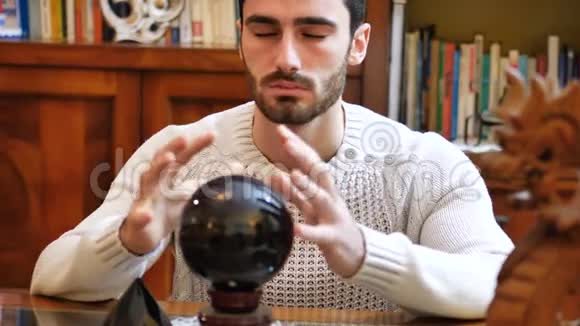 年轻的男性预言家通过观察水晶球预测未来视频的预览图
