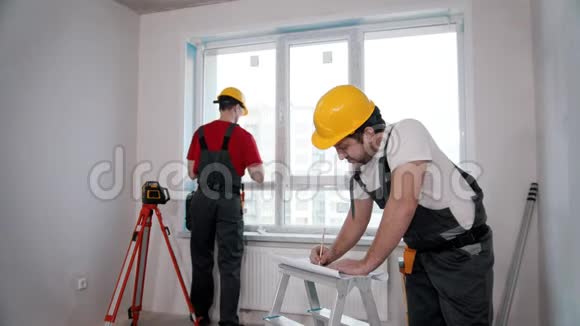 公寓维修一名工人测量房间的窗户并在笔记本上做标记视频的预览图