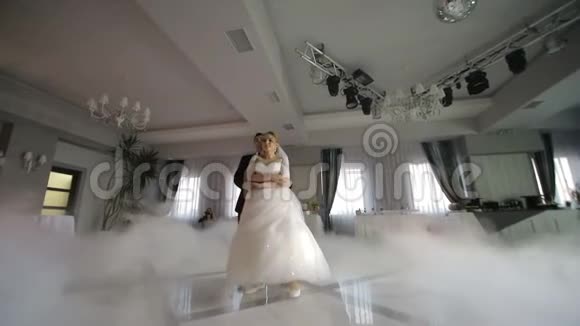 婚礼上的新娘舞会用白光突出的浓烟新婚夫妇的第一支舞蹈视频的预览图